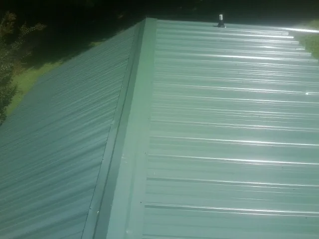 New green metal panels meeting at the ridge of a roof — Flat Roof Repair work by our crew in Drewsey
