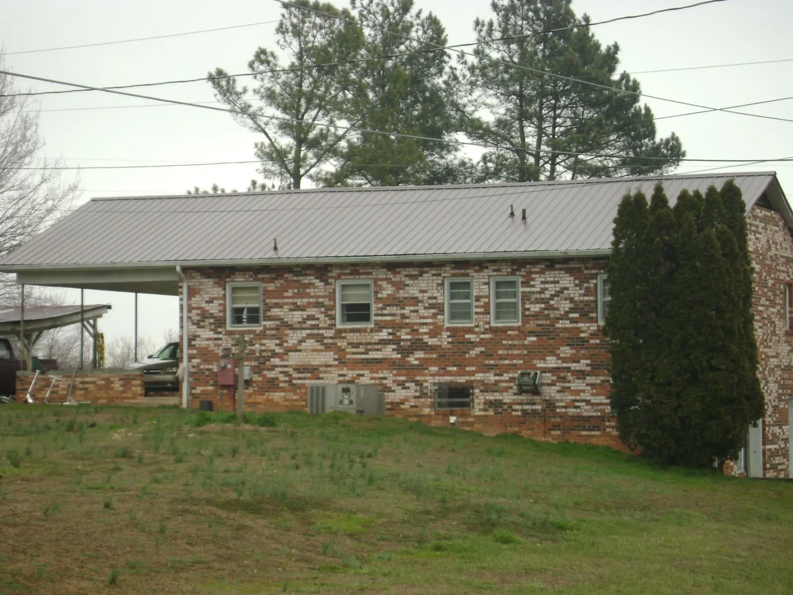 Gray metal roof on a brick split level home with a carport in Drewsey