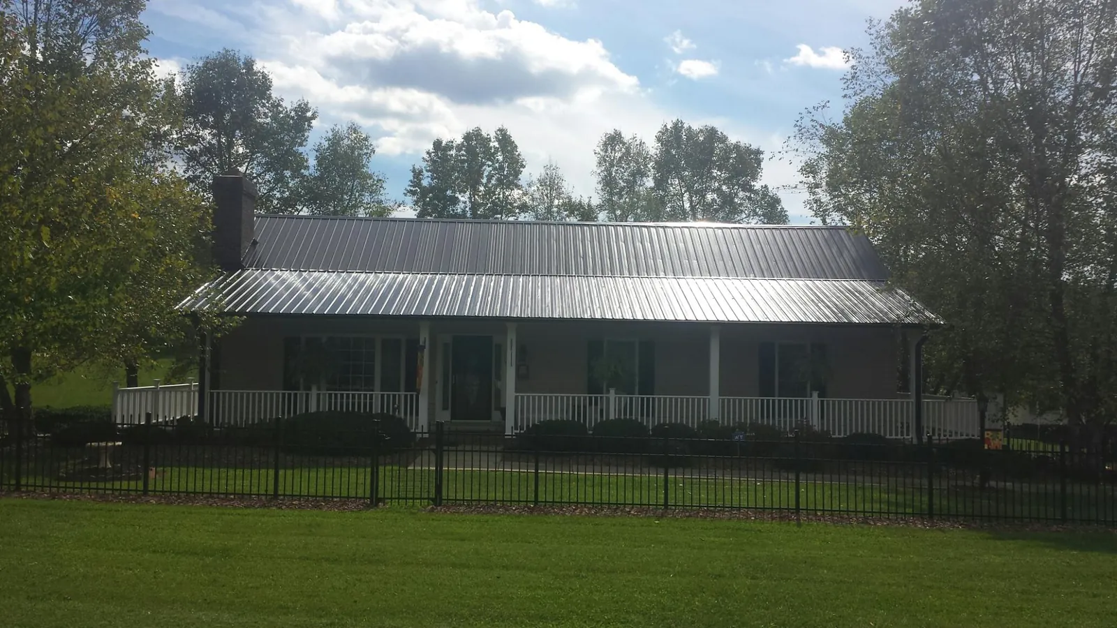 Gray metal roof on a brick ranch with a full width front porch — Gutter Guard Installation work by our crew in Drewsey