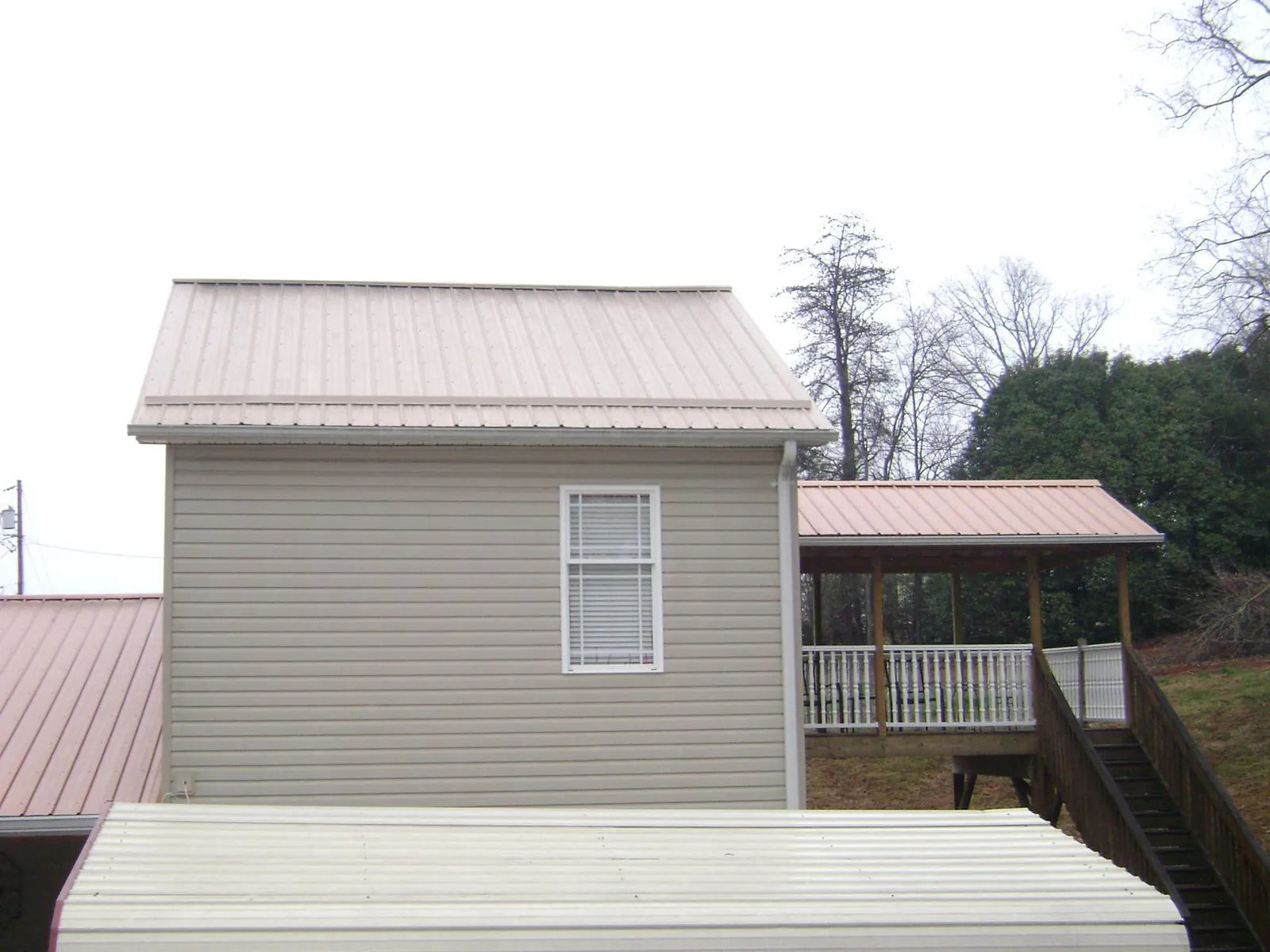 Tan metal roofs on a two story addition and attached porch, from a Roof Replacement job in Drewsey